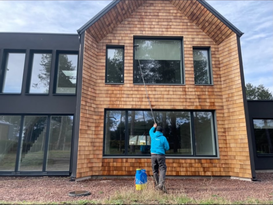 Window cleaner using a water-fed pole on a timber-clad house