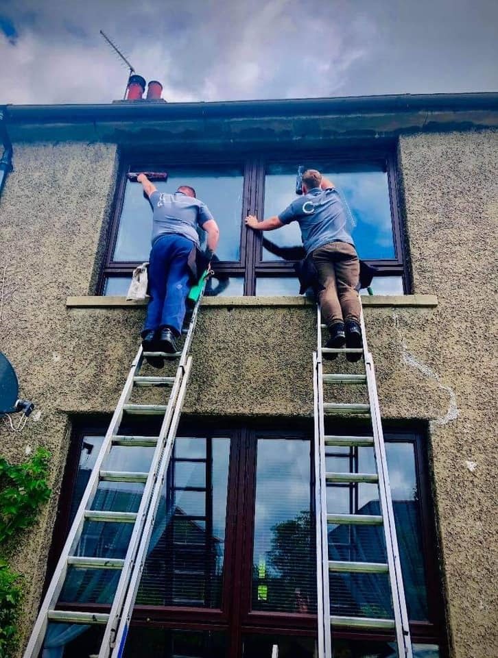 Two Complete Cleaning Specialists window cleaners on ladders cleaning first-floor windows in East Lothian
